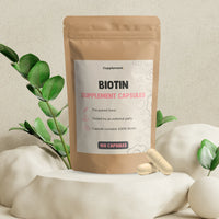 Een hand houdt een Biotine Capsule boven een glas water, klaar om in te nemen.