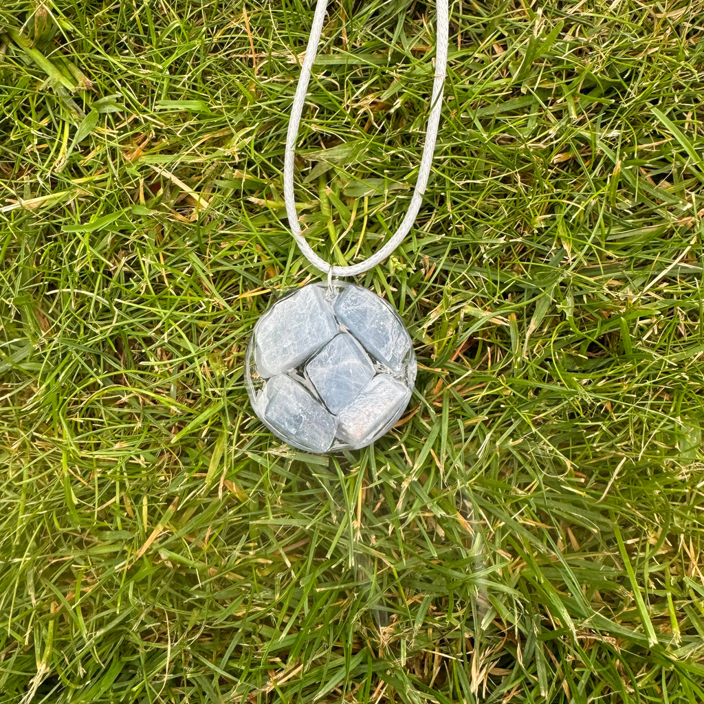 Blauwe Calciet ketting gedragen door een model in een stijlvolle setting, met de blauwe kleur die elegantie en rust uitstraalt, te zien tegen een achtergrond van gras!