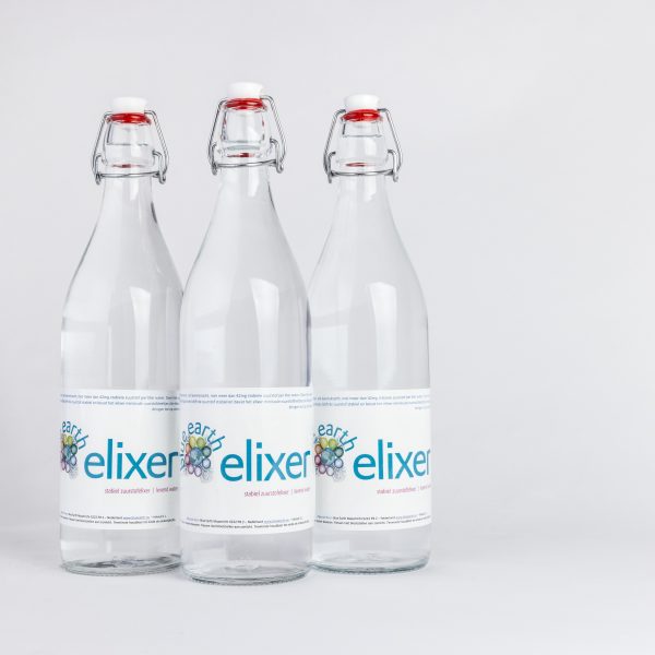 Een verfrissende fles Blue Earth Elixer met puur water, geplaatst in een natuurlijke setting die de zuiverheid benadrukt.