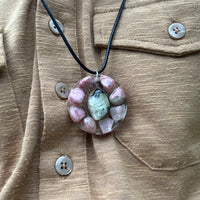 Rodoniet en Serpentijn Edelstenen: Detail van de Rodoniet en Serpentijn stenen in de ketting, symboliseren emotionele genezing en spirituele bescherming.
